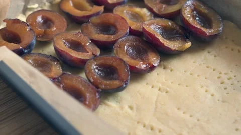 Putting plums on a raw dough in a baking tray for a plum tart. Stock Footage 225110718