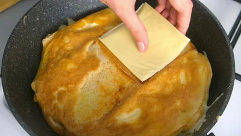 Putting processed cheese on frying bread for sandwich with egg on skillet . Stock Footage 318215616