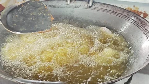 Putting raw battered fish into a frying pan with boiling oil. Video stock 342740393