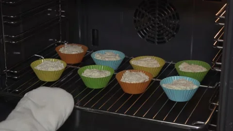 Putting raw cottage cheese muffins into oven Stock Footage 146593219