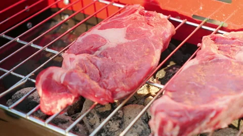 Putting raw red meat on the grill in 4k Stock Footage 153865603
