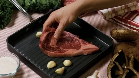 Putting raw steak into the tray, close up panning shot Stockbeeldmateriaal 102609970