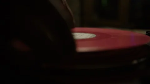 Putting a red vinyl record on turntable and putting stylus needle on Stock-Footage 129572846