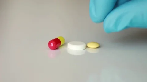 Putting red, yellow and white pills Stock Footage 76994979