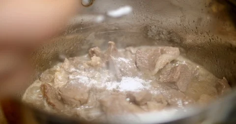 Putting salt and pepper in the boiling meat in a saucepan Stock Footage 88048686