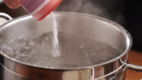 Putting salt into boiling water. Stock Footage 151120220