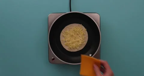 Putting a slice of cheese on shredded cheese and a tortilla 1 Stock Footage 132203721