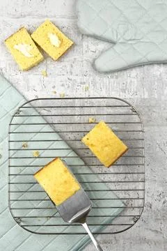 Putting a slice of cornbread onto a cooling rack. Stock Photos