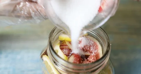Putting sliced figs, lemon and sugar in jar to make fresh fig preserve Stock Footage 115932038