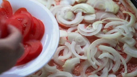 Putting sliced tomatoes on pizza dough Stock Footage 84100283