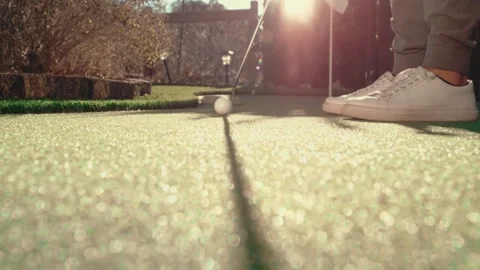 Putting Slow Motion Golden Hour Sun Flare White Sneakers Putter Ball Wood Fence Video stock 334537860