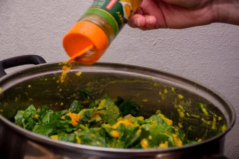 Putting some indian orange curry in the green salad mixed with mango Stock Photos