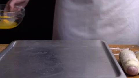 Putting some of the sausage rolls on a baking sheet Stock Footage 111770617