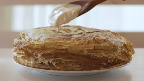 Putting a spoon of sour cream on a large hot stack of pancakes. Pancake week. Stock Footage 104370352
