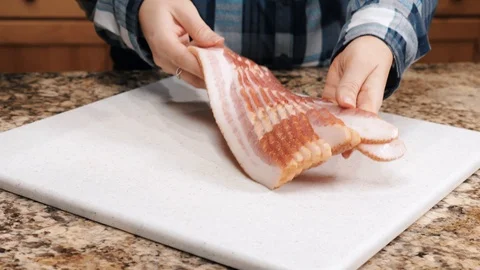 Putting stack of bacon slices on the white board Stockbeeldmateriaal 102605939