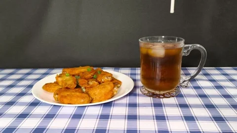 Putting a straw into a cup of cola with ice cubes, served with a plate of d.. Stockbeeldmateriaal 318133524