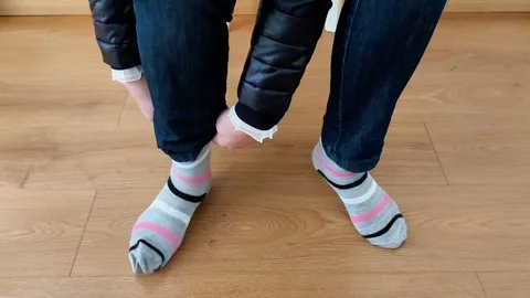 Putting On Striped Socks While Standing on Wooden Floor Indoors Video stock 328003406