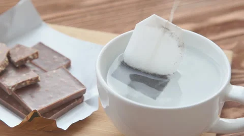 Putting sugar and tea bag in a glass mug with hot water Stock Footage 68974378