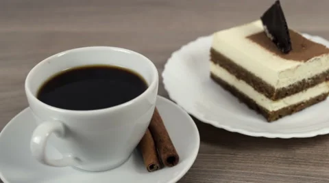 Putting sugar cube into a cup of coffee on a wooden table with tasty cake Stock Footage 58593397