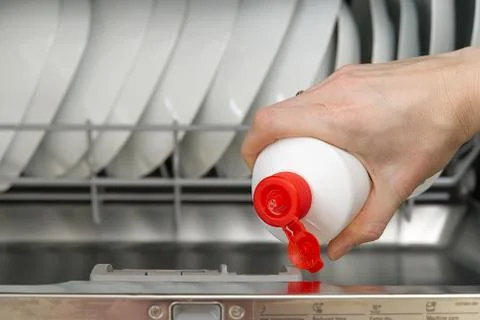 Putting tab into full dishwasher close up. integrated dishwasher machine full Stock Photos