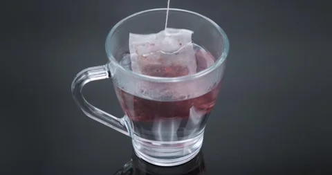 Putting tea bag in a glass mug with hot water Stock Footage 149014150