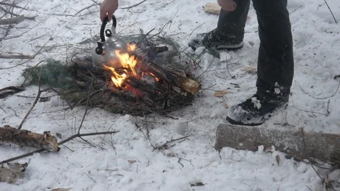 Putting tea kettle on open fire in winter with snow off grid lifestyle Stock Footage 121219116