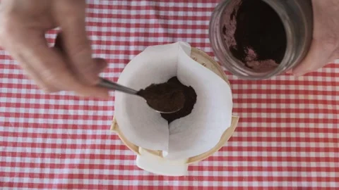 Putting teaspoons of coffee into a paper filter Stock Footage 307742571