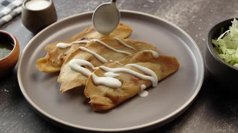 Putting thick sour cream in diagonal lines on some mexican molotes Stock Footage 281445227