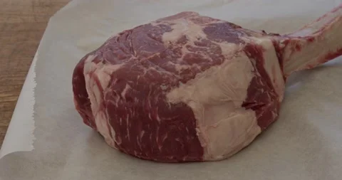 Putting a tomahawk ribeye steak onto a board Stock Footage 153462531