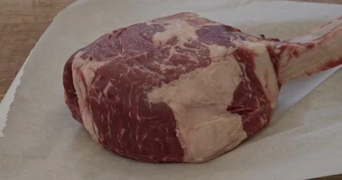 Putting a tomahawk ribeye steak onto a board Stock Footage 156591362