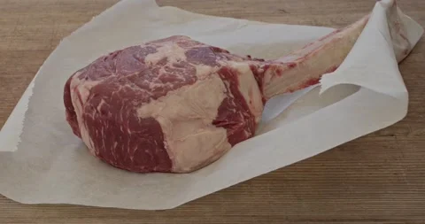 Putting a tomahawk ribeye steak onto a board Stock Footage 158627661