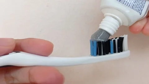 Putting toothpaste on a black toothbrush Stock Footage 146250078