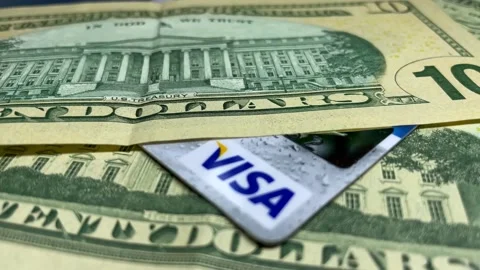 Putting twenty dollar bank notes on Visa card. Cash and electronic funds Stock Footage 155383613