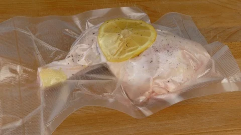 Putting vacuum-packed raw chicken leg sous vide 4k Stockbeeldmateriaal 125181979