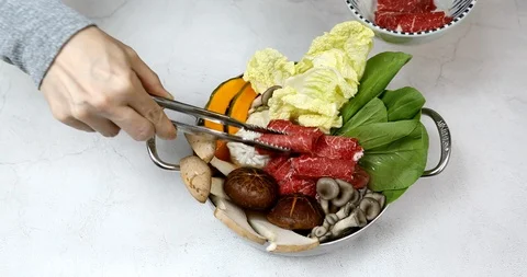 Putting vegetables and beef in pot for shabu shabu Stock Footage 117779824