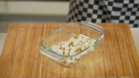 Putting white bread cubes into a glass dish while making croutons Stock Footage 267090738