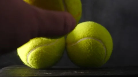 Putting yellow tennis ball on table isolated on black with smoke swelling slow Video stock 206836366