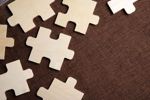 Puzzle elements on a brown background as a riddle Stock Photos