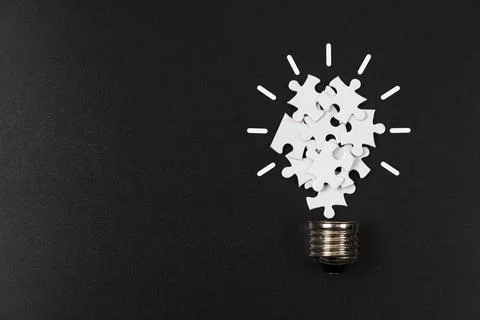 Puzzle Lightbulb on Black Background Stock Photos