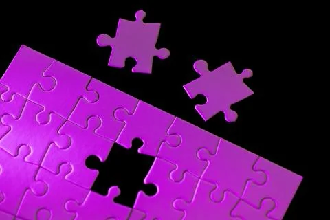 A puzzle with a missing piece and two pieces of the puzzle on the ground Stock Photos