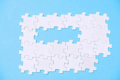 A puzzle with a missing piece is shown on a blue background Stock Photos