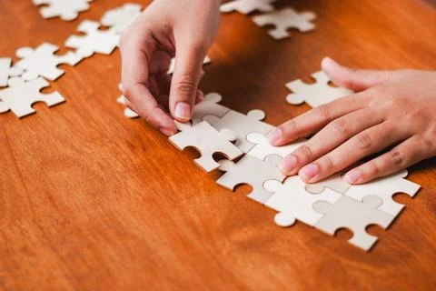 Puzzle solving activity at home engaging hands with unfinished pieces woode.. Stock Photos