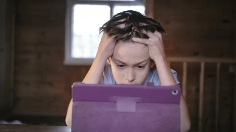 Puzzled Contemplation: Boy Reflecting at the Table with Tablet, Clutching Head Stock Footage 239640655