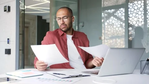 Puzzled disappointed businessman having difficulty with paperwork sitting  Stock Footage 311622228