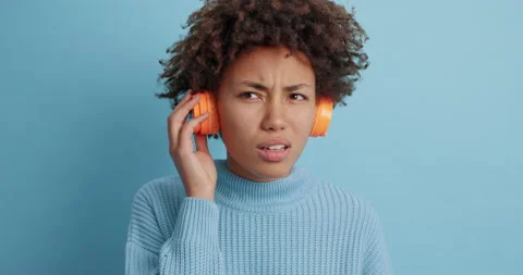 Puzzled displeased dark skinned young woman listens song shows dislike gesture Stock Footage 144914296