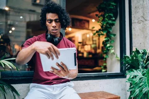 Puzzled hipster guy making online booking and banking on gadget Stock Photos