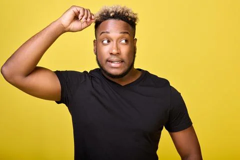 Puzzled look of a black guy of athletic build on a yellow background Stock Photos