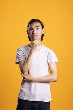 Puzzled man looking upward with hand on chin in isolated studio 写真素材