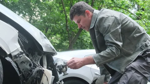 Puzzled man sets broken headlight of vehicle on ground Stock Footage 316836054