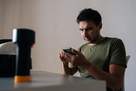 Puzzled technician reading instructions on smartphone while cleaning filter of Stock Photos